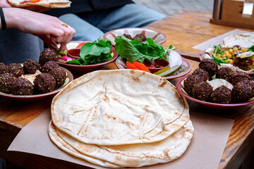 Close up pita bread, falafel, humus and vegetables on wooden background. Vegetarian food and middle...