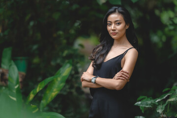 Beautiful girl in the garden on a sunny day, sexy Asian woman wearing black dress and posing to take a portraits photo, Art fashion spring model girl in day home forest, nature outdoor scene