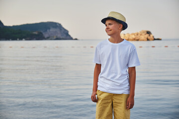 Portrait of a stylish teenage boy on the seashore. The concept of summer vacation and travel.