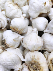 Garlic bulbs pile close up background texture. Fresh vegetables produce at farmers market or grocery store.
