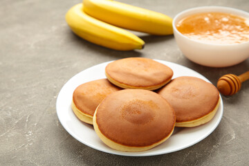 Homemade banana pancakes with butter in plate on grey background. Space for text