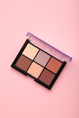Palette of basic eyeshadows on pink background. Makeup concept. Vertical photo