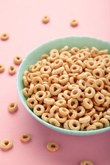 Bowl of sugar-coated corn flakes on pink background.