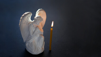 praying angel and candle close up on abstract dark blurred background. Easter, Orthodox palm Sunday. Good Friday. symbol of Christianity, faith, prayer. Church religious holiday. template for design