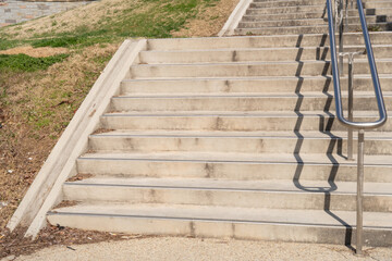 Looking up short flight of concrete outdoor park steps with stainless steel hand rails from a wide...