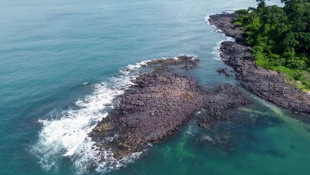 Aerial of the foamy ocean waves hitting the rocky Bureh Beach in Sierra Leone