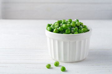 Freshly frozen green peas on a white wooden background