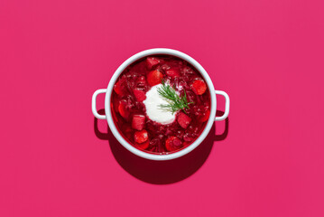 Beetroot soup bowl minimalist on pink table. Borscht with sourcream.