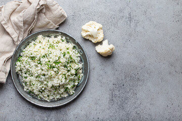 Raw cauliflower rice or couscous with dill on plate, healthy low carbohydrates vegetable side dish...