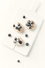 Little mascarpone tart with fresh bilberries on wooden background. Top view.	