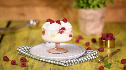 Vanilla ice cream with fresh raspberry in a glass bowl.