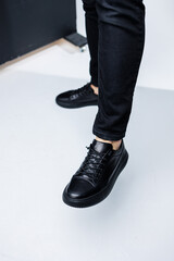Close up of male legs in black jeans and black leather casual sneakers. Comfortable men's demi-season shoes