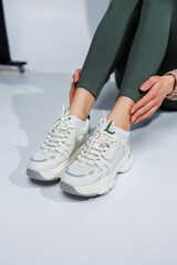 Slender female legs in leggings and white stylish casual sneakers. Women's comfortable summer shoes.