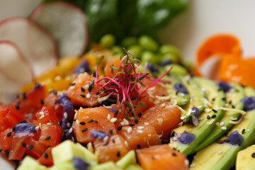 Delicious poke bowl with salmon fish fillet and fresh vegetables. Exotic pescatarian food prepared for lunch in a cafe