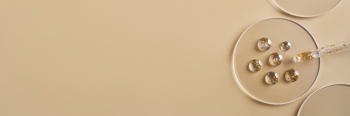 Samples of gel cosmetic products with gold in a Petri dish on beige banner