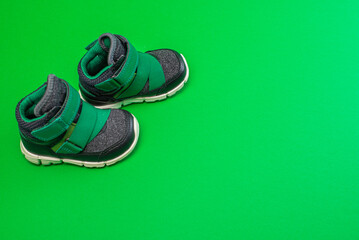 Colorful baby shoes on bright green background in child's room