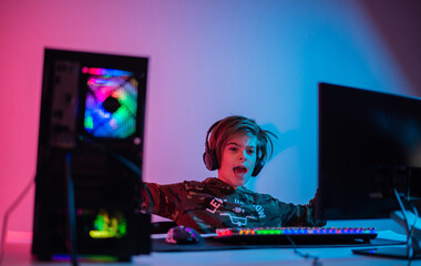Teenager playing video game on PC. He is raising his fist in a victory gesture. online multiplayer video game 