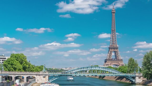 Eiffel tower at the river Seine timelapse from Grenelle bridge in Paris, France. Isle of the Swans and ship on river and traffic on the street at sunny summer day. Arch brige over the water