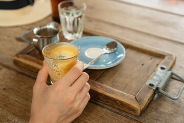 person holding a empty glass of coffee on a wooden table 