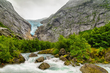 the glacier and the river with an ice waterfall falling down the cliff in Norway