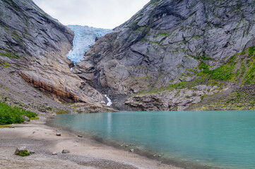 glacial lake and the ice waterfall falling down the mountain in Norway