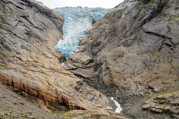 the ice of the glacier falling down the cliff in Norway