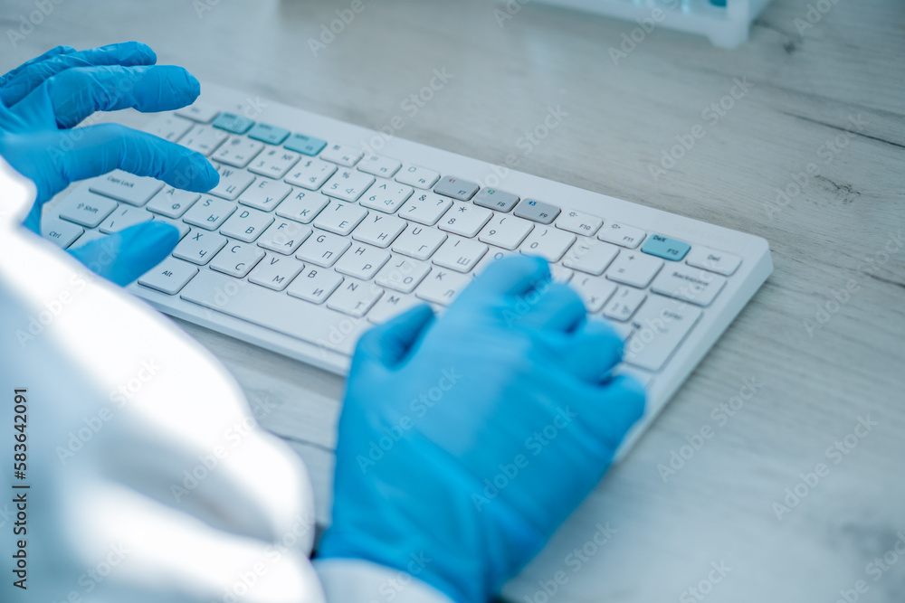 Poster a female researcher sits at a workplace in a laboratory, behind a personal computer monitor. against