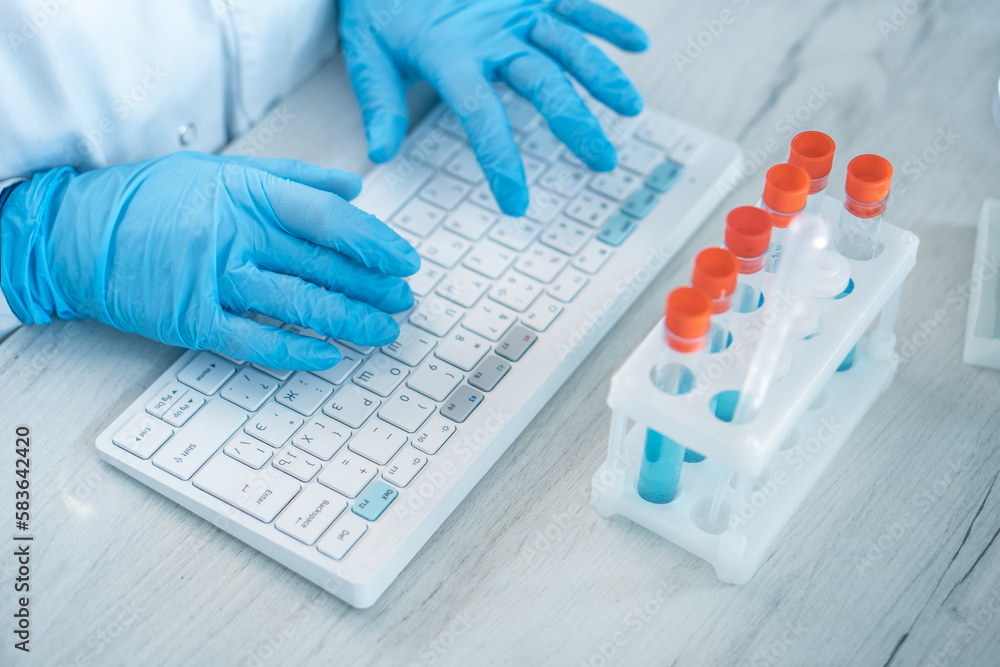 Poster a female researcher sits at a workplace in a laboratory, behind a personal computer monitor. against