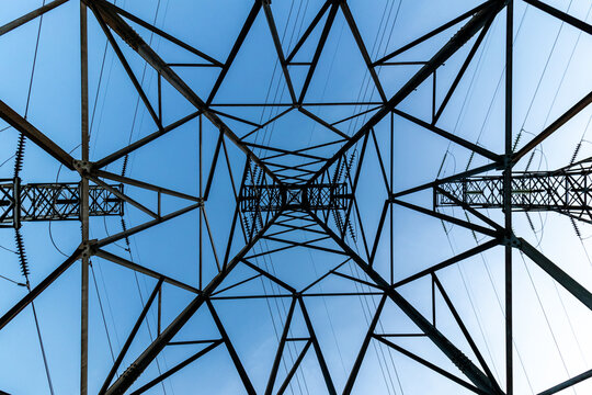 Tr&ecirc;s torres de transmiss&atilde;o formando desenho geom&eacute;trico em belo c&eacute;u azul.