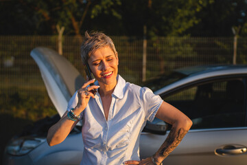 one woman mature female standing on the road in the evening sunset by the broken vehicle car...