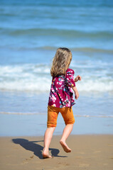 Fototapeta na wymiar A little girl is running on the beach