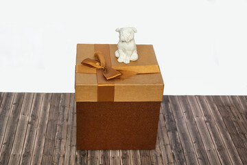 The concept of giving and receiving gifts. Close shot of white toy dog next to brown gift box with bow