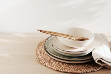 Modern ceramic tableware on beige wooden table with copy space.  Trendy plates, cutlery and linen...