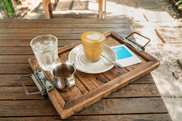Heart shape latte art in small glass with icy water and brown sugar on wooden tray on wooden table,Latte Piccolo on serve