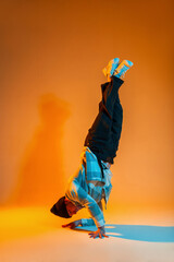 Stylish trendy professional breakdancer guy in trendy fashion clothes with a shirt is dancing on...
