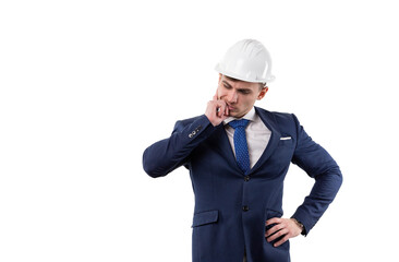 Handsome man in a suit and helmet is thinking about solving a problem. Concept in the studio on a white background.