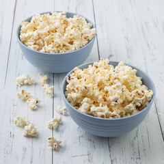 Popcorns on a blue bowls over white wooden table