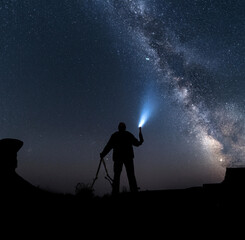 silhouette of a person with a torch under milky way rising
