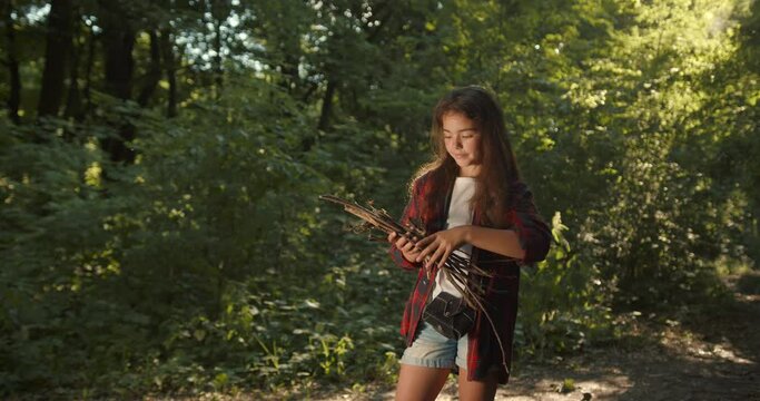 Teenage girl hiker setting a bonfire in forest