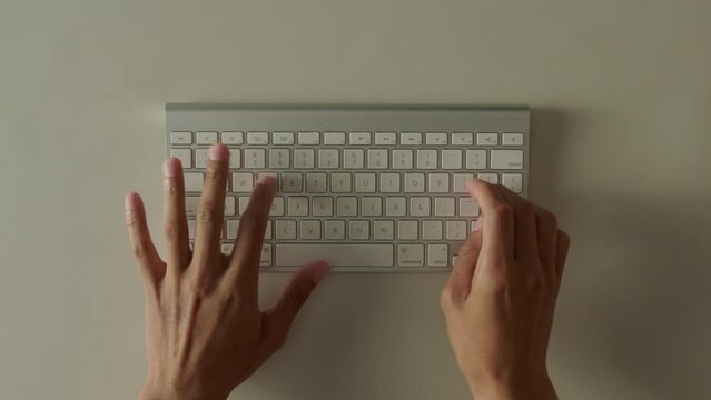 Caucasian hands typing on keyboard at white table