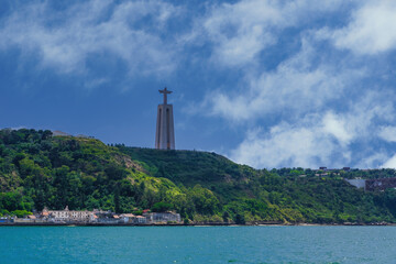 Fototapeta na wymiar Lisbon, Portugal day sea view of Cristo Rei statue, Christ the King Sanctuary, against blue sky with clouds over the Tagus River.