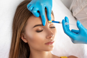 Cosmetologist makes rejuvenating anti wrinkle injections on the face of a beautiful woman. Female...