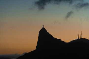 Obraz premium Sunset in the bay of Guanabara, cove and beaches of Rio de Janeiro, Brazil with its buildings, boats and landscape. Christ the Redeemer on top of Corcovado. Reflection of the sky in the sea