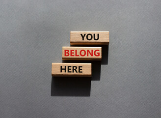 You belong here symbol. Wooden blocks with words You belong here. Beautiful grey background. Business and You belong here concept. Copy space.