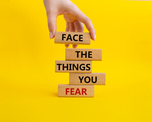 Face the things you fear symbol. Wooden blocks with words Face the things you fear. Beautiful yellow background. Businessman hand. Business and Face the things you fear concept. Copy space.