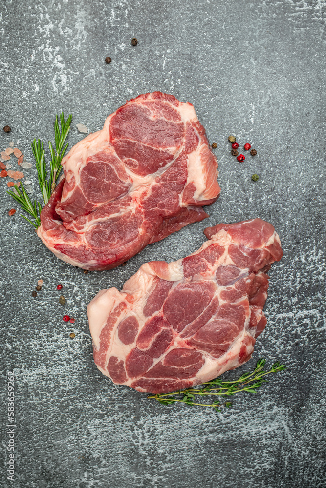 Wall mural raw pork steaks on a cutting board with spices Raw meat pork steaks with seasoning. place for text, top view