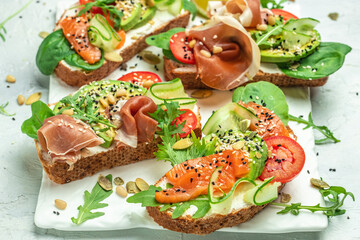 Open sandwich set with cream cheese, prosciutto, salmon, avocado and fresh greens. Keto, ketogenic diet, low carb, high good fat , healthy food. top view. place for text