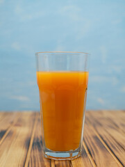 Fresh juice, mix fruits, orange drink on a blue background. Glass with orange cocktail.