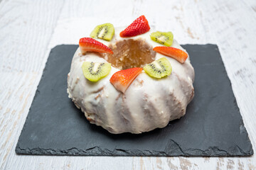 A gugelhupf (kuglof) with fruits on a black plate
