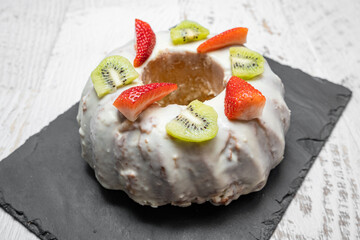 A gugelhupf (kuglof) with fruits on a black plate
